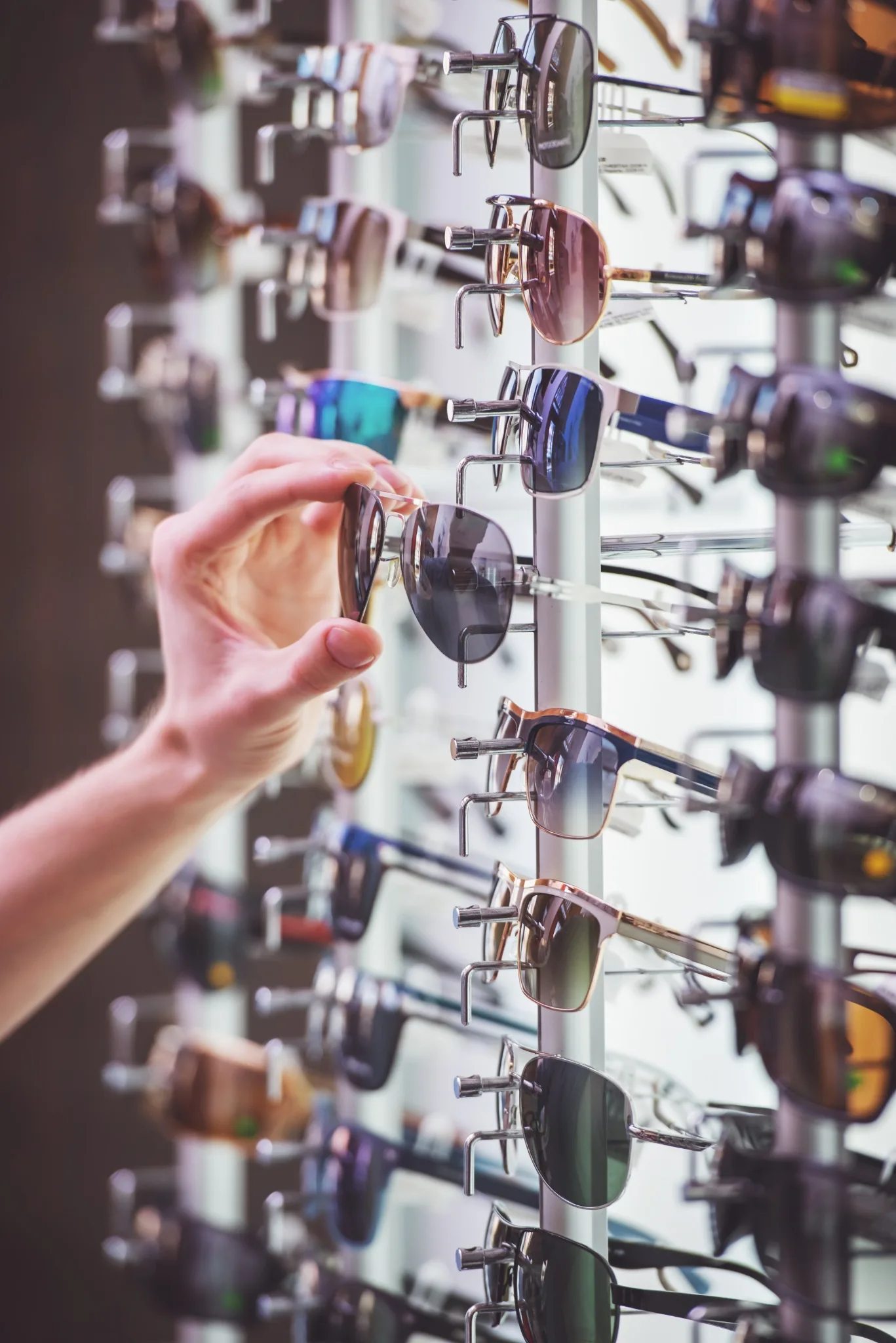 Hand choosing sunglasses from a retail display