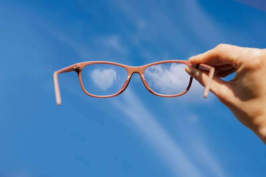 Spectacles held against a blue sky